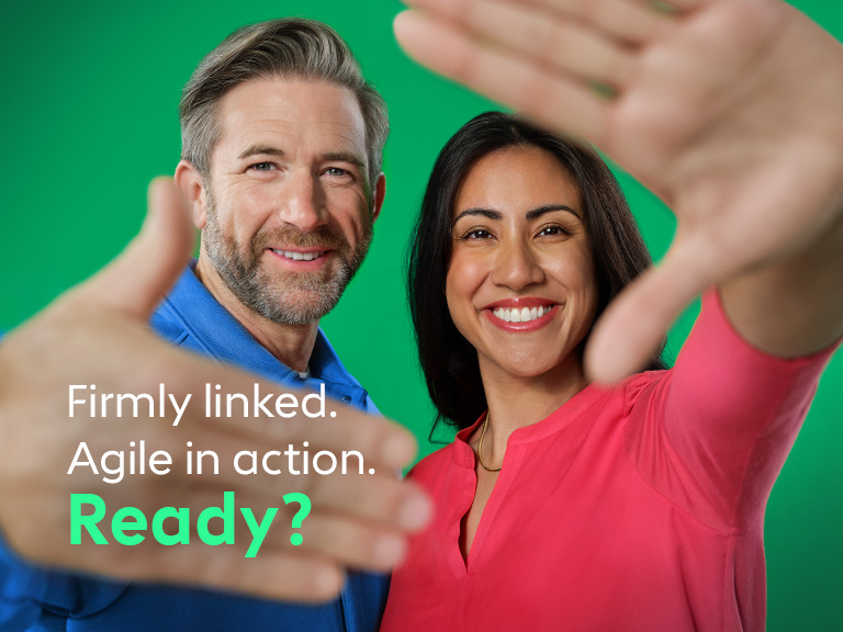 Two people smile at the camera and extend their hands invitingly.