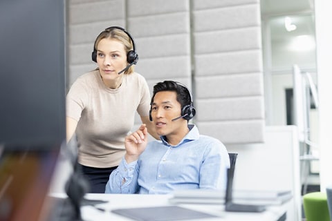 Zwei Personen diskutieren bei der Arbeit am PC