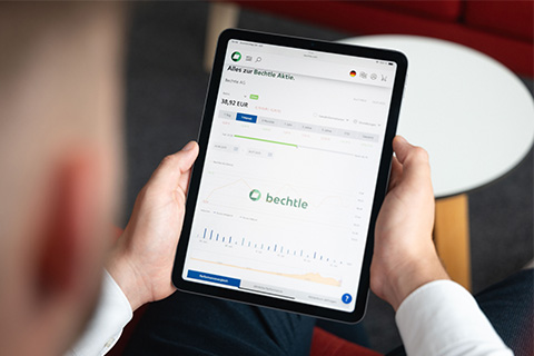 Mann hält ein Ipad auf dem ein Aktienchart abgebildet ist