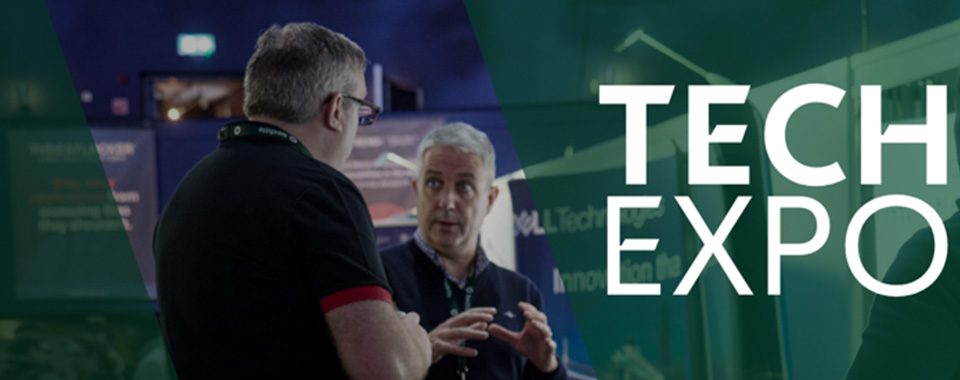 Two people engaged in conversation at a technology expo focusing on exchange and innovation