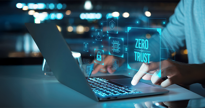 Ein Mann tippt auf einem Laptop. Über dem Laptop leuchtet der Text „Zero Trust“.