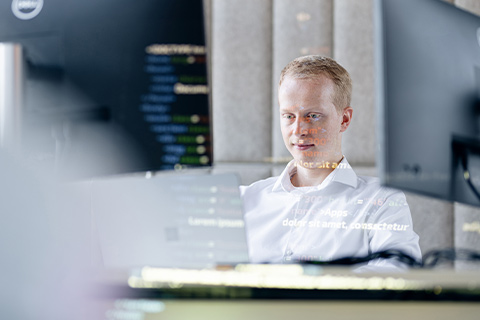 A young man looks at a monitor and works.