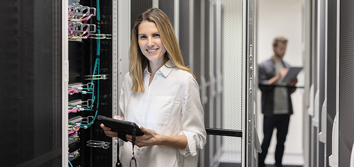 Eine glückliche Frau arbeitet in einem Serverraum.